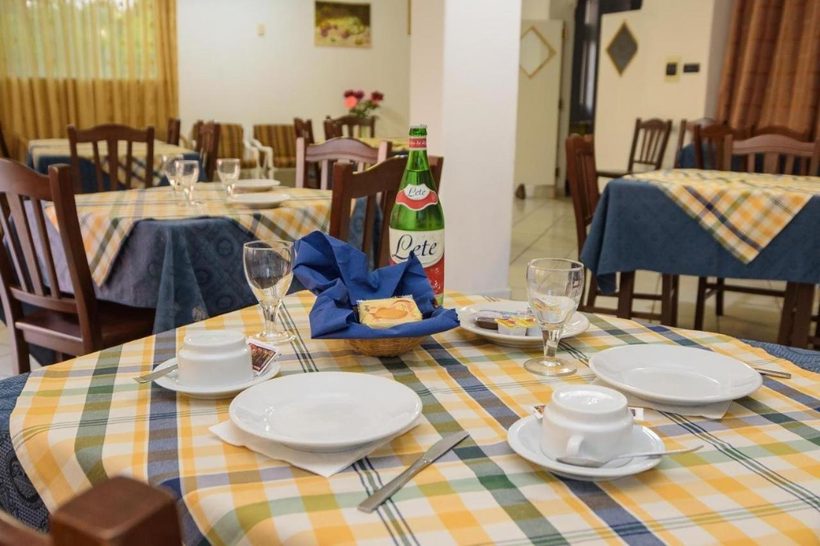 Tavolo della colazione apparecchiato con cura, con stoviglie e tovaglia a quadri