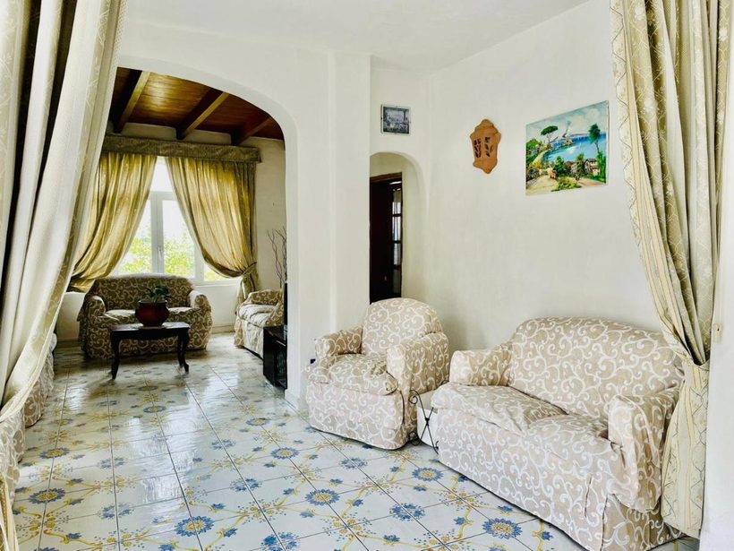 Salotto comune con divani, archi eleganti e pavimento in maioliche